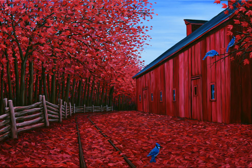 A red barn behind a row of trees in deep red autumn leaf
