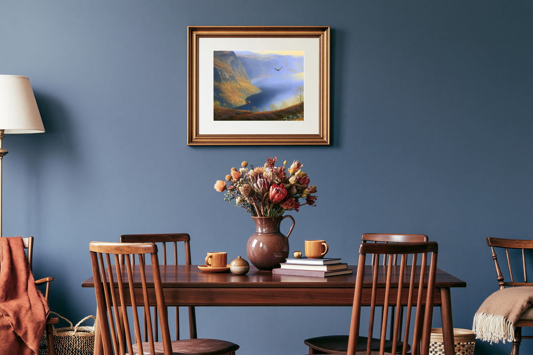 A framed fjord painting on a deep blue dining room wall