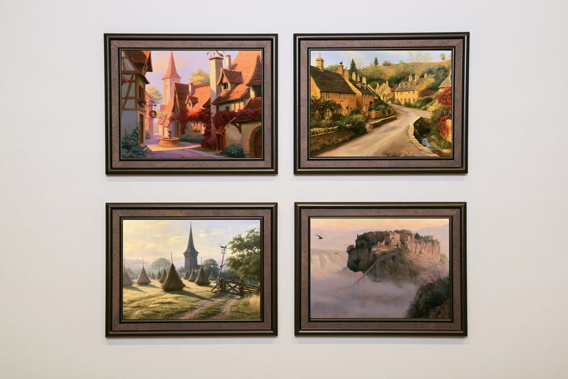 Four framed village paintings hung as a square gallery wall